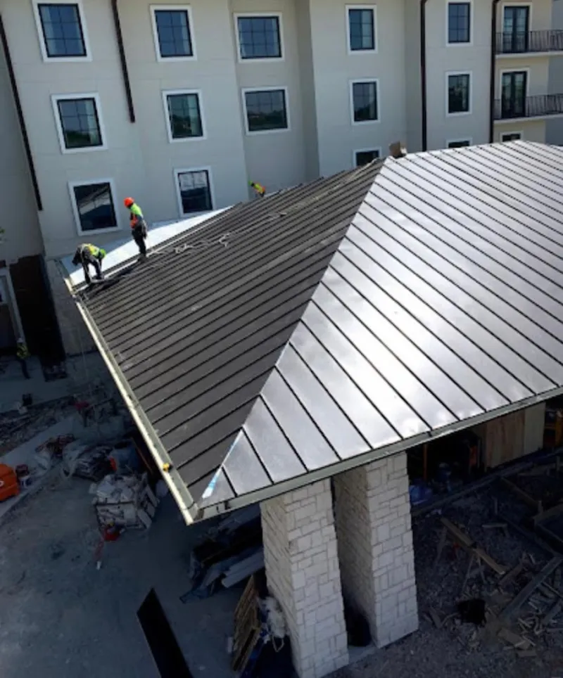 Crew installing standing seam metal roof panels on a commercial project in Chino